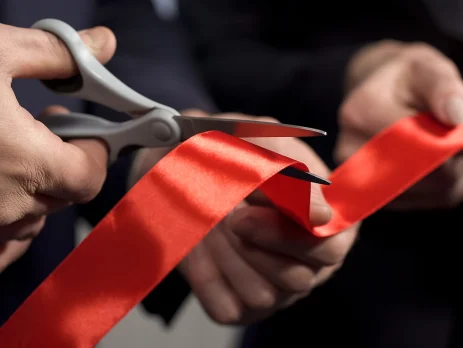 hands cutting red ribbon close-up