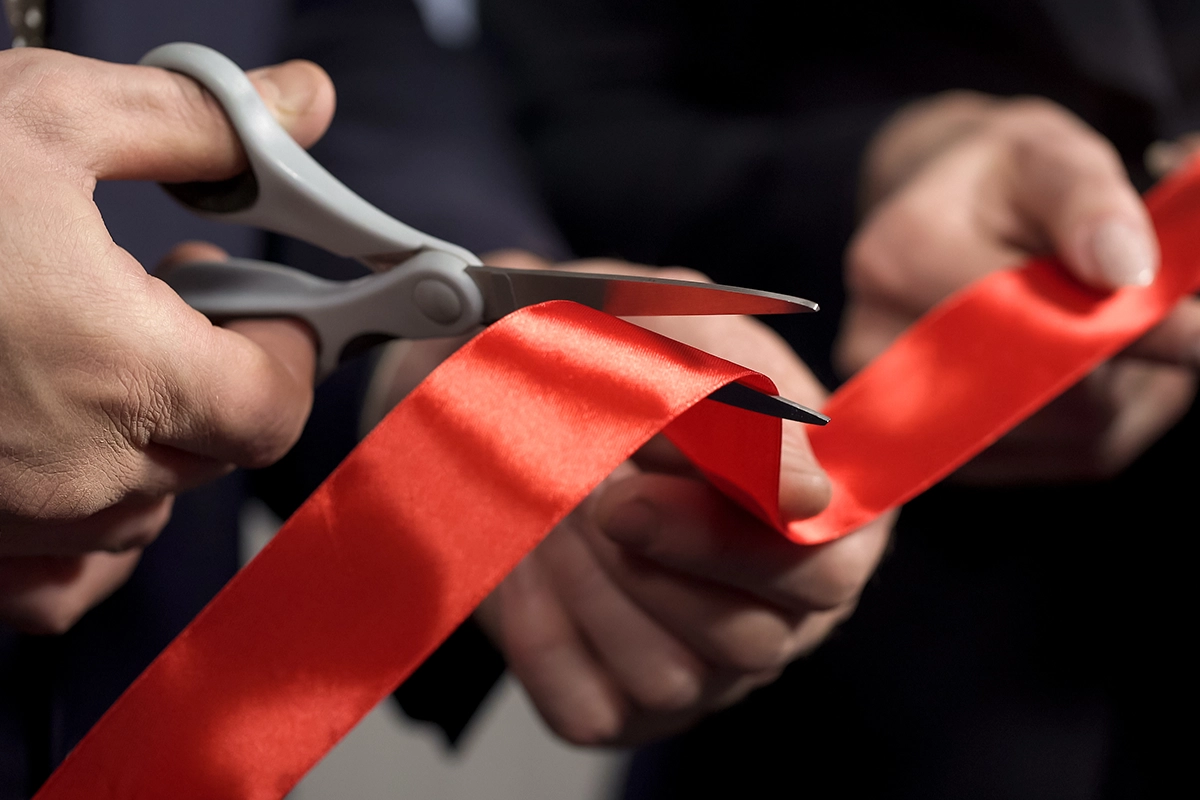 hands cutting red ribbon close-up