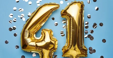 Gold balloons spelling out 41 on a blue background with silver confetti