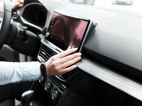 Woman twists the controls on the car radio.